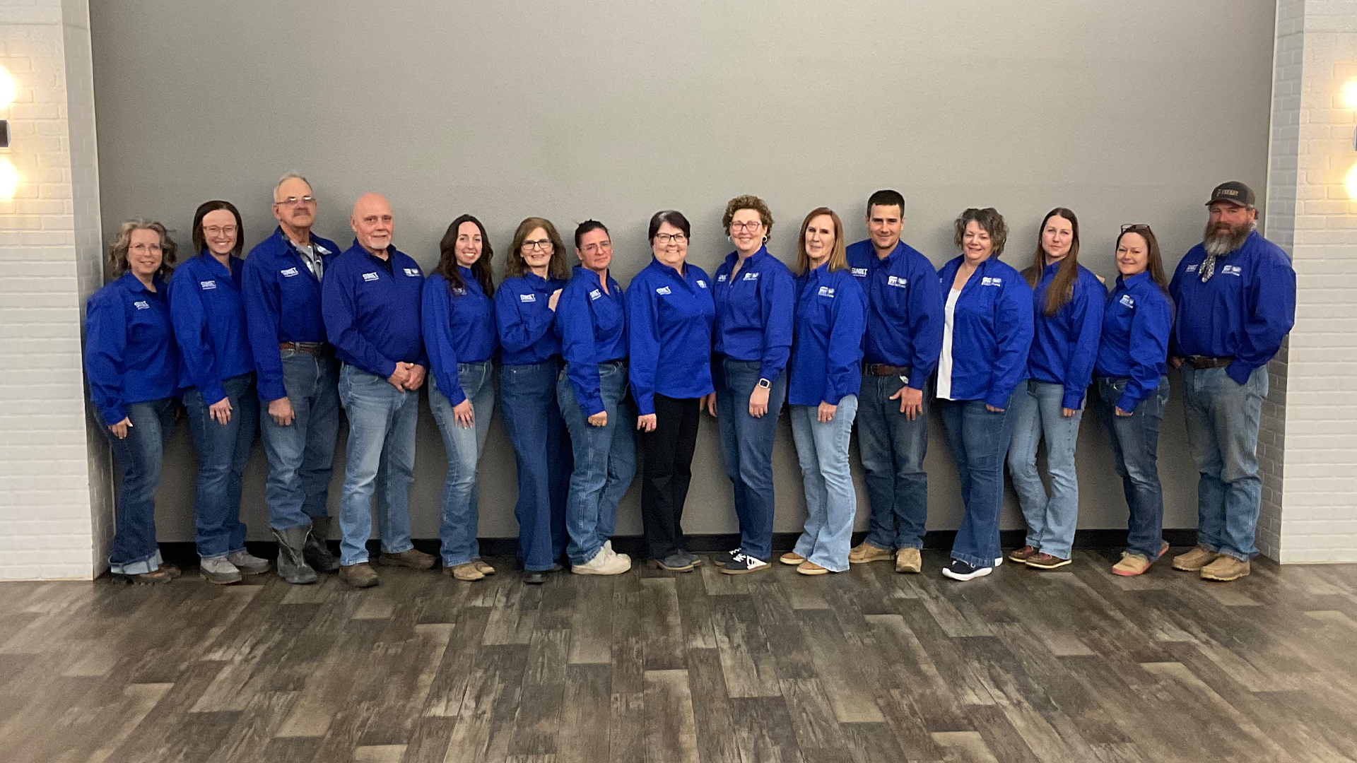Group of people in blue jackets holding an "Energy City Ex" banner, posing together in a brightly lit indoor space.